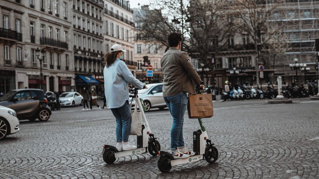 Dos ciudadanos circulan con patinetes eléctricos de alquiler por las calles de París