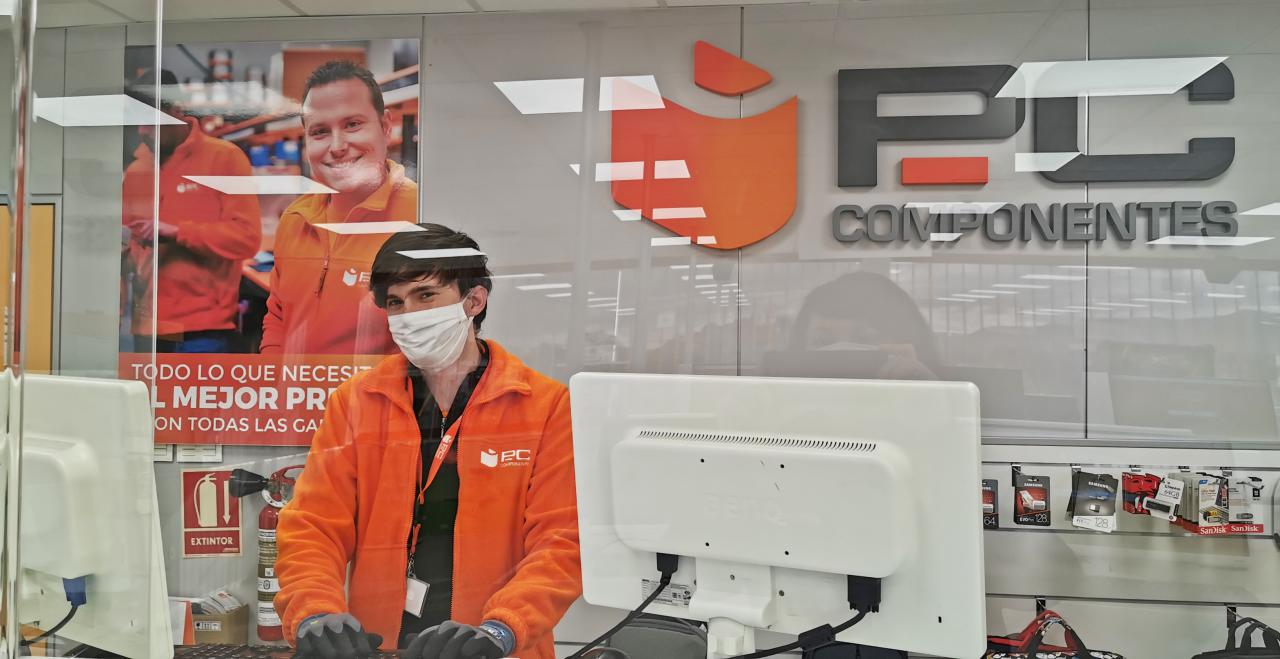Un empleado de la compañía atiende a través de una pantalla de protección en la tienda de Pc Componentes de Alhama de Murcia