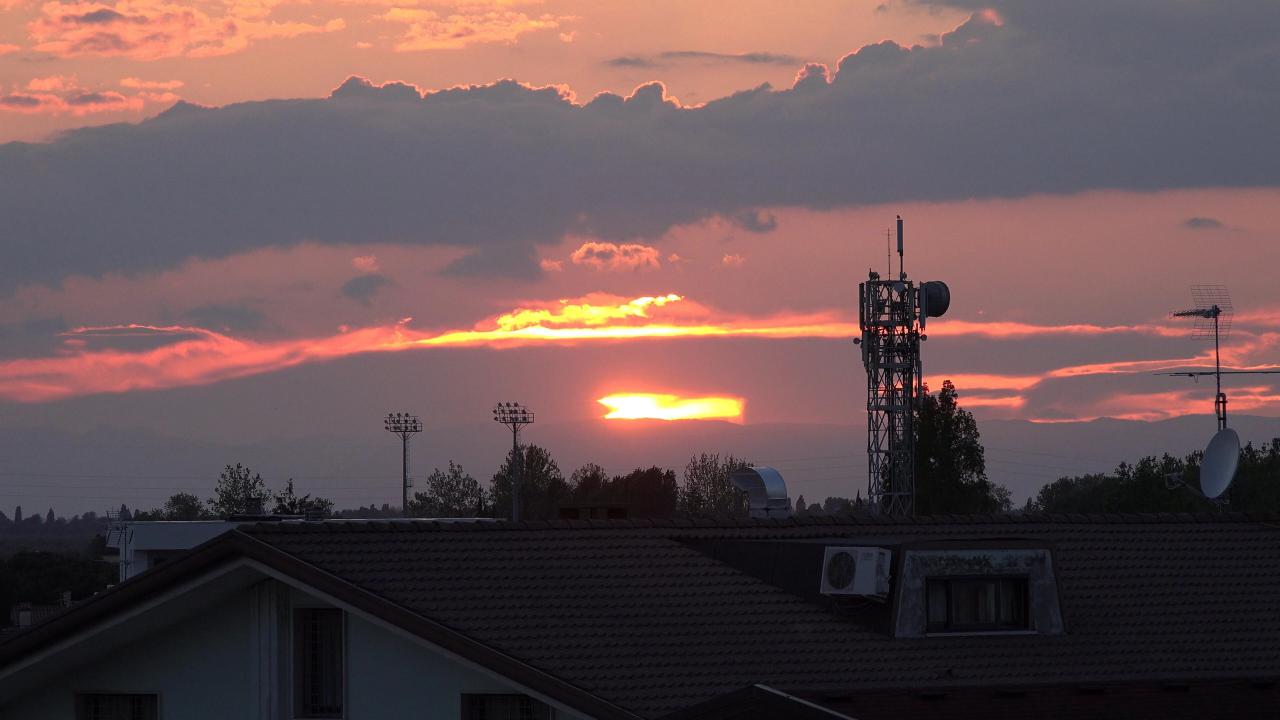 Una torre de telecomunicaciones se alza tras una casa ante una puesta de sol
